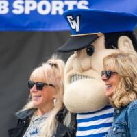 Louie stands with two alumni posing for a photo